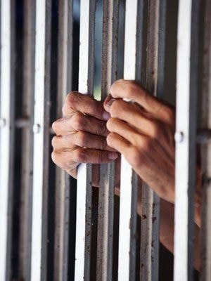 Hands gripping jail bars representing bail bond services
